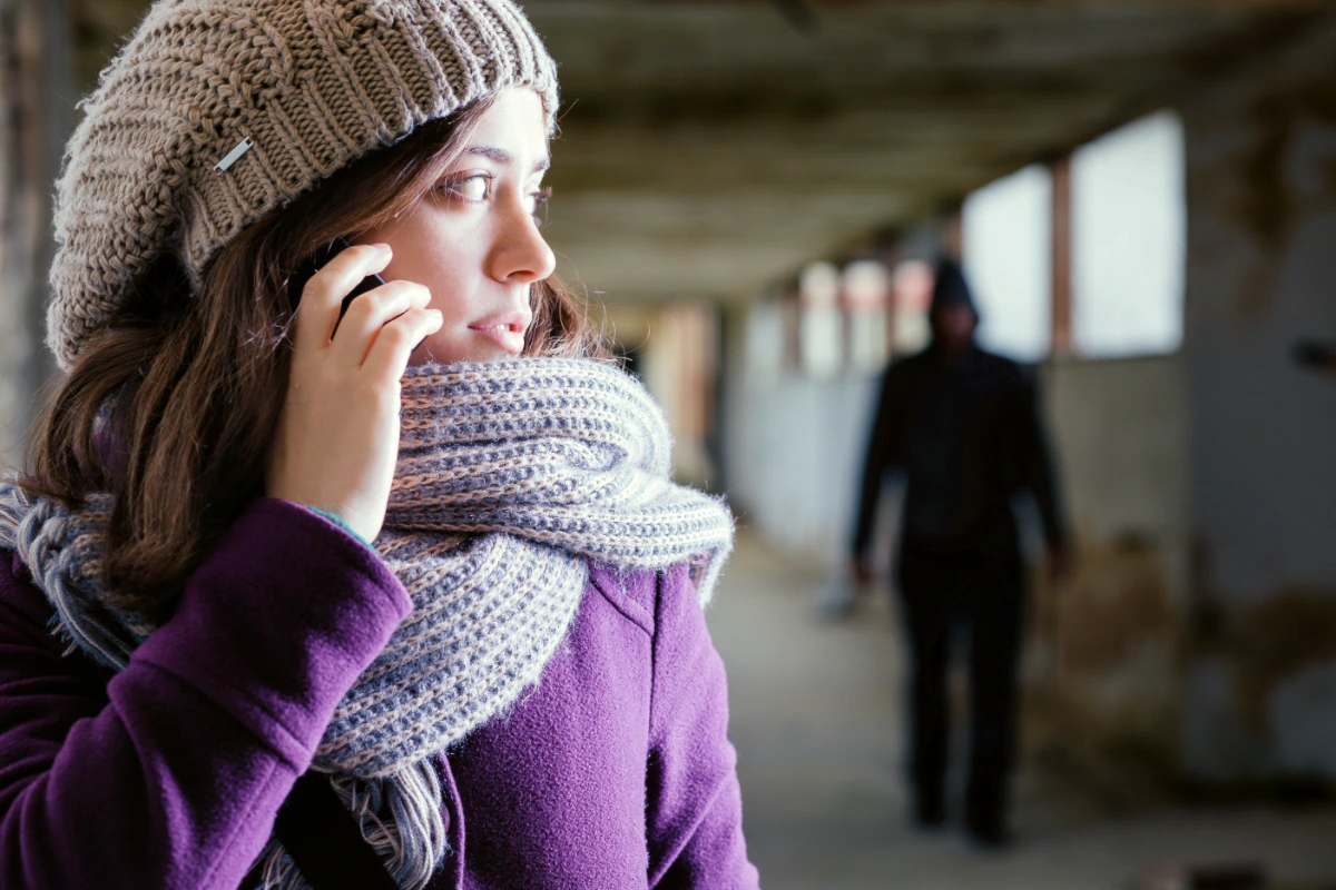 a woman on a cell phone being followed by a stalker